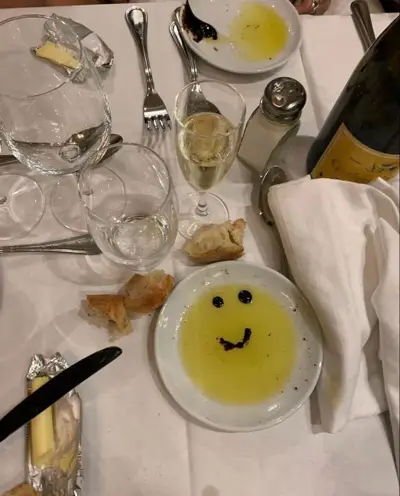 A smiling olive oil plate, bread and glasses at the dinner table